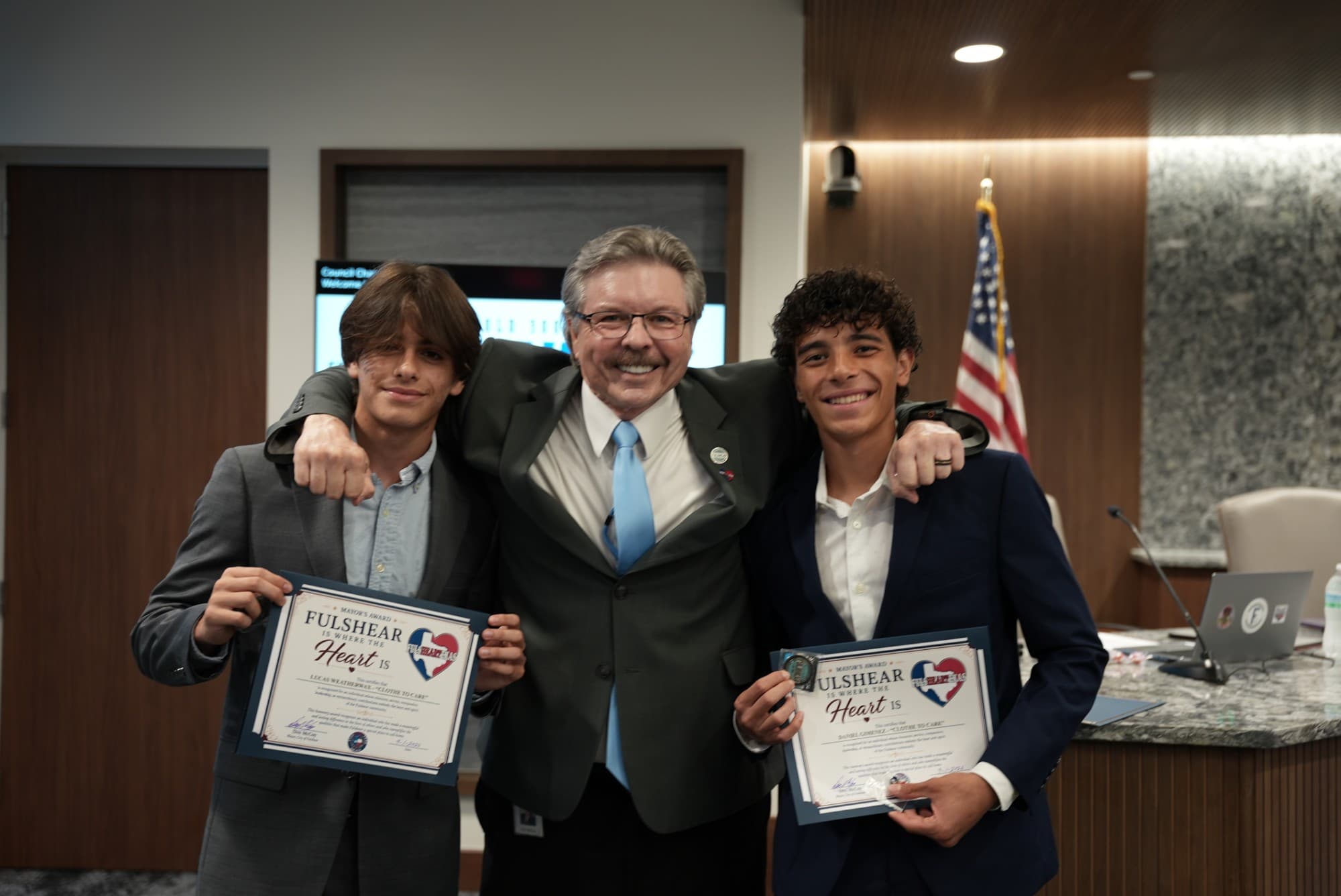Lucas Weatherwax, Fulshear Mayor Don McCoy, and Daniel Gimenez at the Heart of Fulshear Award presentation, with Lucas and Daniel holding their award certificates.
